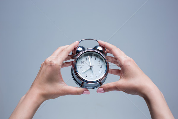 Stock photo: The female hands and old style alarm clock 
