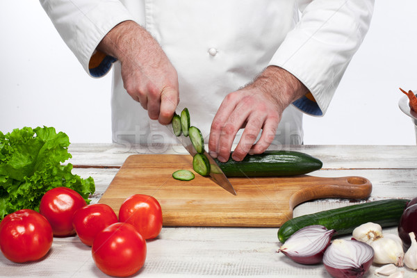Chef cutting a green cucumber in his kitchen Stock photo © master1305