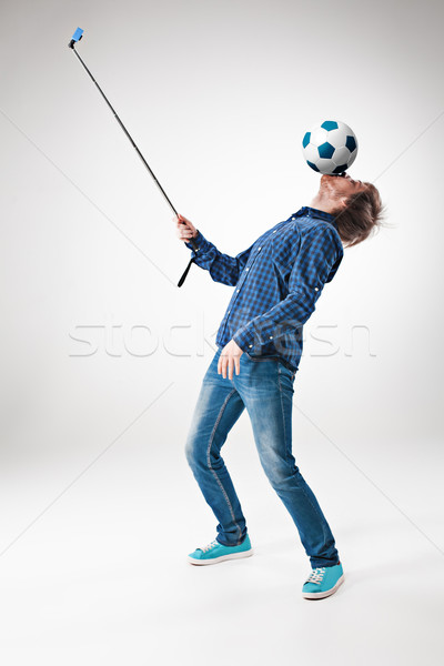 The portrait of man with ball, holding selfie stick on white background Stock photo © master1305