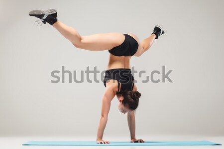 Beautiful sporty girl standing in acrobat pose or yoga asana Stock photo © master1305