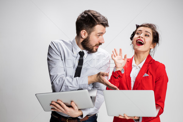 The young businessman and businesswoman with laptops communicating on gray background Stock photo © master1305