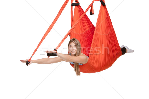 Young woman doing anti-gravity aerial yoga in hammock on a seamless white background. Stock photo © master1305