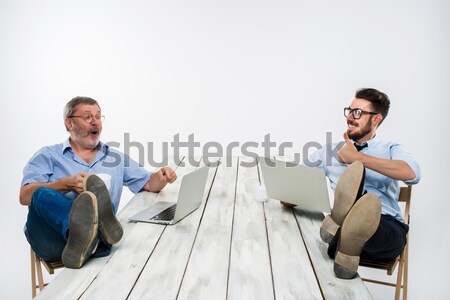 The two businessmen with legs over table working on laptops Stock photo © master1305
