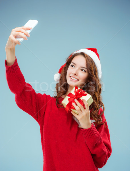 Girl dressed in santa hat with a Christmas gift and phone Stock photo © master1305