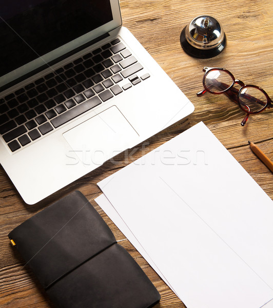 The laptop, blank paper, glasses and small bell on the wooden table  Stock photo © master1305