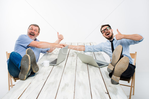 The two smiling businessmen with legs over table Stock photo © master1305