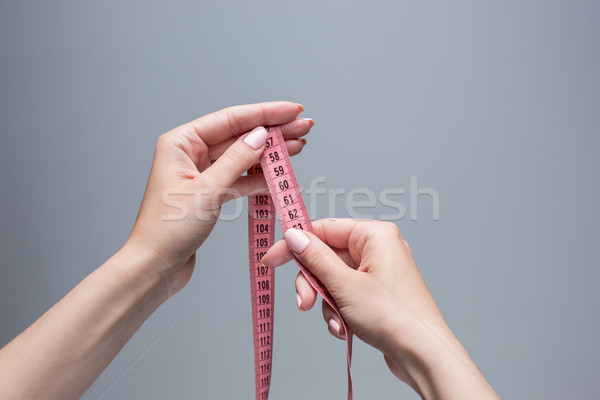 The tape in female hands on gray background. Weight loss, diet Stock photo © master1305