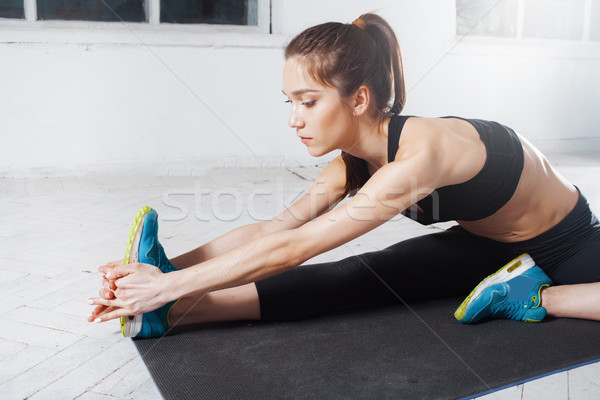Beautiful slim brunette  doing some stretching exercises in a gym Stock photo © master1305