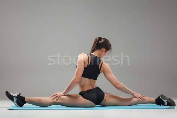 Muscular young woman athlete sitting in the split on gray  Stock photo © master1305