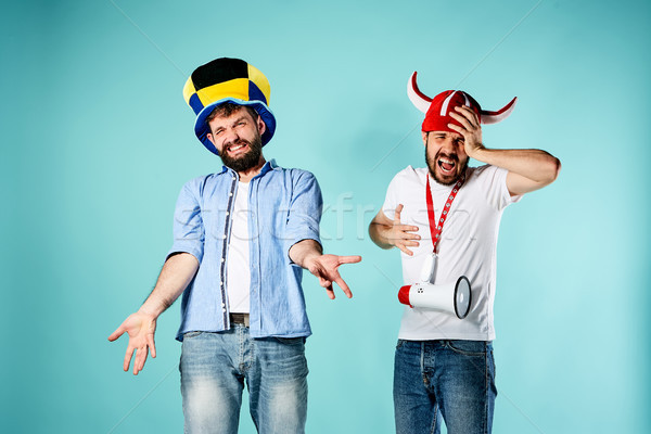 The two football fans with mouthpiece over blue Stock photo © master1305