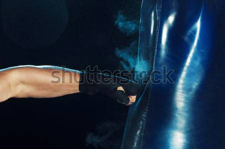 Male boxer boxing in punching bag with dramatic edgy lighting in a dark studio Stock photo © master1305