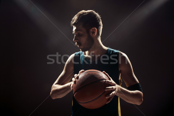 Silhouette view of a basketball player holding basket ball on black background Stock photo © master1305