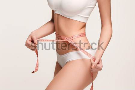 Stock photo: Woman holding meter measuring perfect shape of her beautiful body 