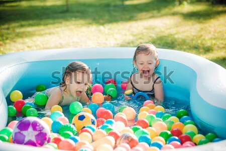 The two little baby girls playing with toys in inflatable pool in the summer sunny day Stock photo © master1305