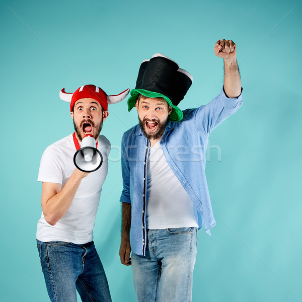 Stock photo: The two football fans with mouthpiece over blue