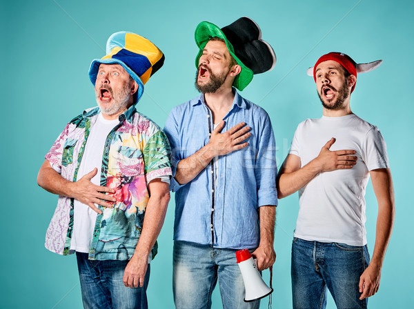The three football fans singing the national anthem over blue Stock photo © master1305