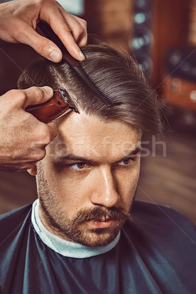 The hands of young barber making haircut to attractive man in barbershop Stock photo © master1305