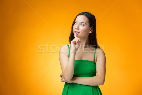 The thinking Chinese girl on yellow background Stock photo © master1305