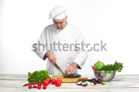 Chef cutting a green cucumber in his kitchen Stock photo © master1305