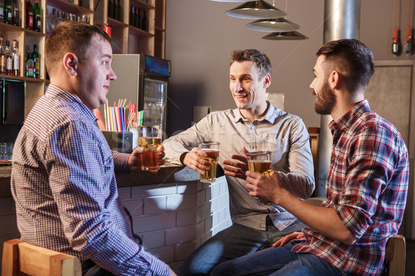 Happy friends drinking beer at counter in pub Stock photo © master1305