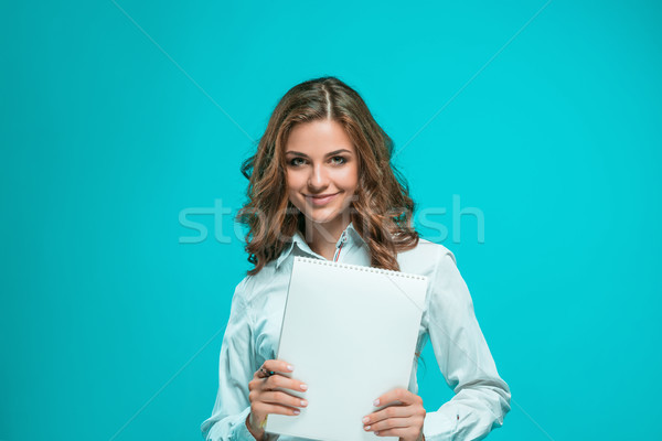 The smiling young business woman with pen and tablet for notes on blue background Stock photo © master1305