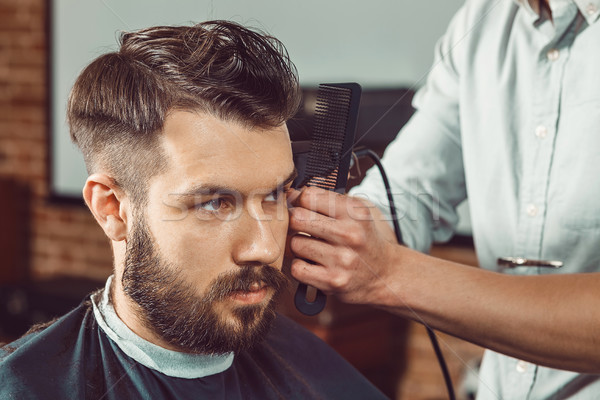 The hands of young barber making haircut to attractive man in barbershop Stock photo © master1305