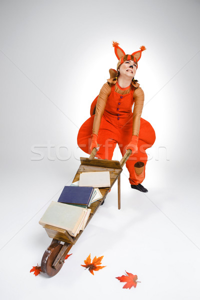 Stock photo: Young woman in image of squirrel with cart and books