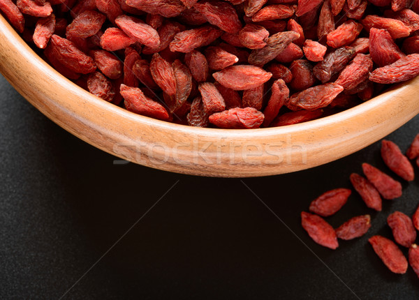 Wooden Bowl Full of Dried Goji Berries on the Black Table Stock photo © maxpro