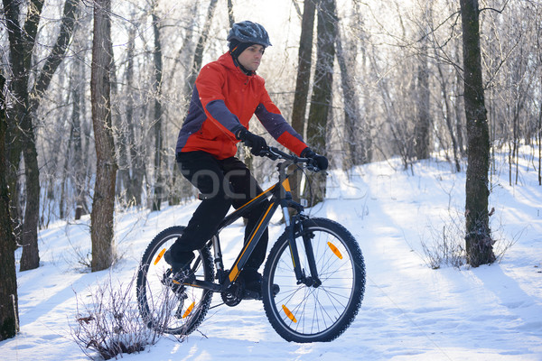 Stock photo: Mountain Biker Riding Bike on the Snowy Trail in the Beautiful Winter Forest Lit by Sun