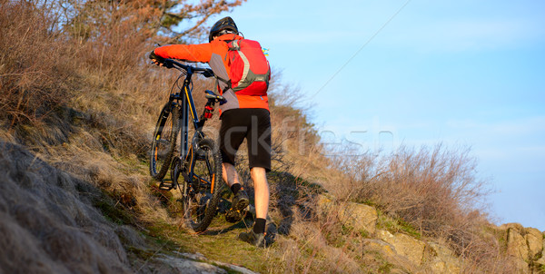 Enduro Cyclist Taking his Mountain Bike Up the Rocky Trail. Extreme Sport Concept. Space for Text. Stock photo © maxpro