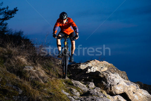 Enduro Cyclist Riding the Bike on the Rock at Night. Extreme Sport Concept. Space for Text. Stock photo © maxpro