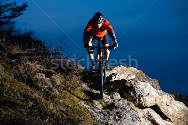 Enduro Cyclist Riding the Bike on the Rock at Night. Extreme Sport Concept. Space for Text. Stock photo © maxpro
