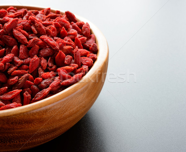 Wooden Bowl Full of Dried Goji Berries on the Dark Table Stock photo © maxpro