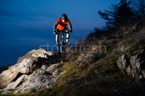 Enduro Cyclist Riding the Bike on the Rock at Night. Extreme Sport Concept. Space for Text. Stock photo © maxpro