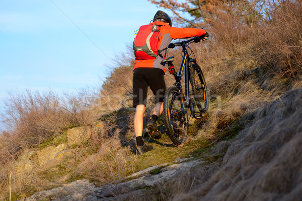 Enduro Cyclist Taking his Mountain Bike Up the Rocky Trail. Extreme Sport Concept. Space for Text. Stock photo © maxpro