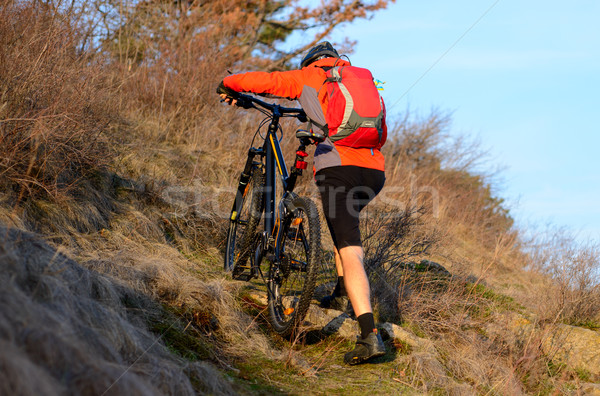 Enduro Cyclist Taking his Mountain Bike Up the Rocky Trail. Extreme Sport Concept. Space for Text. Stock photo © maxpro