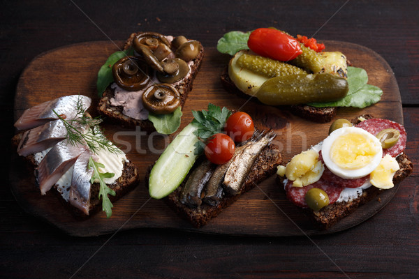 Variety of open sandwiches of buttered dense, dark rye bread with different toppings. Danish smorreb Stock photo © maxsol7