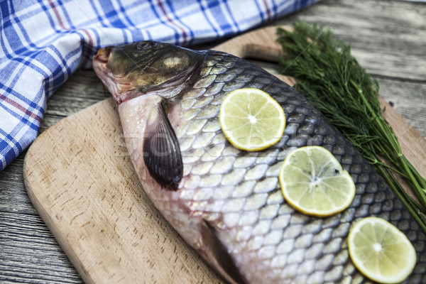 A large fresh carp live fish lying on a wooden board with a knife and slices of lemon and with salt  Stock photo © mcherevan