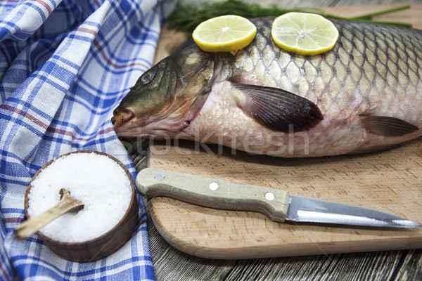 A large fresh carp live fish lying on a wooden board with a knife and slices of lemon and with salt  Stock photo © mcherevan