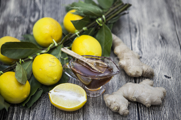 The composition of glass vase with floral honey and wooden spoon with lemon and ginger on a wooden b Stock photo © mcherevan