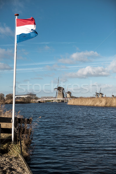 Old windmill with the Netherlands flag. White clouds on a blue sky, the wind is blowing. Stock photo © mcherevan