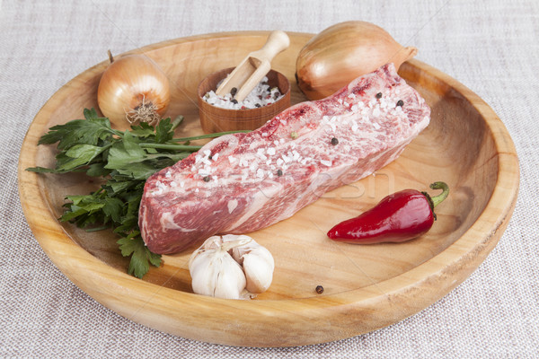 A piece of fresh marbled beef, chili pepper, parsley, onion, garlic, ribs lie on a wooden tray Stock photo © mcherevan
