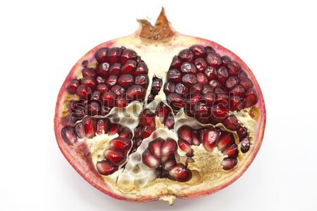Pomegranates have broken into pieces with red berries on a porcelain plate on a white background. Stock photo © mcherevan
