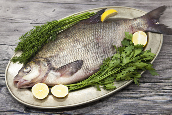 A large live bream river fish  fish lying on a on on an iron tray with a knife and slices of lemon a Stock photo © mcherevan