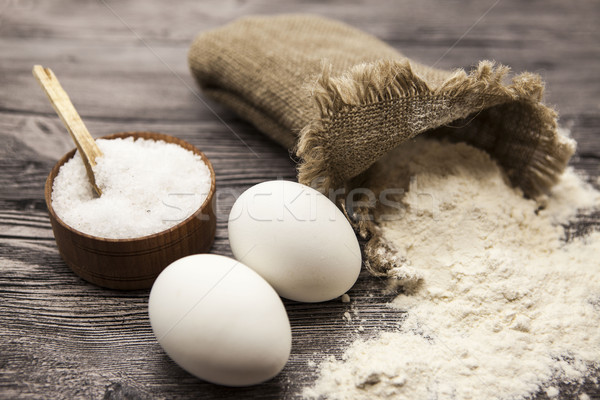 Wheat flour in a canvas bag, a large salt shaker wood, raw eggs: set for making homemade bread dough Stock photo © mcherevan