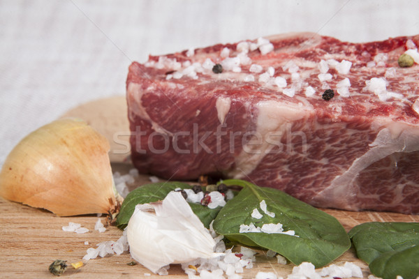 Close-up piece of fresh marbled beef, chili pepper, parsley, onion, garlic, ribs lie on a wooden tra Stock photo © mcherevan