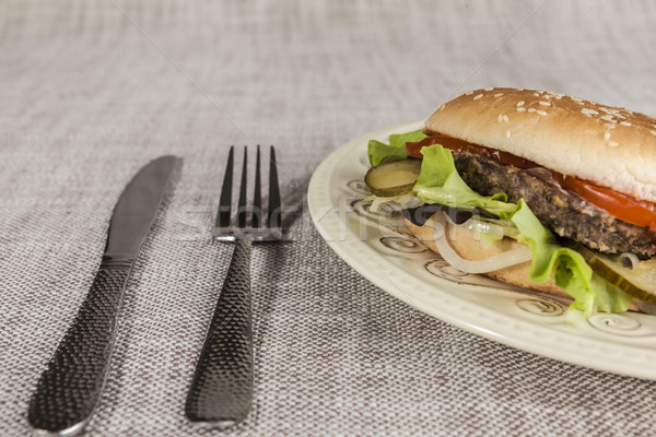 Fresh hamburger with a chop of marbled beef and fresh vegetables on a plate with a fork and knife Stock photo © mcherevan