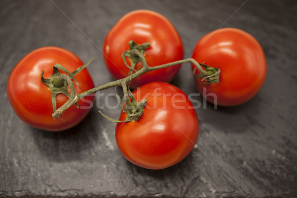 Fresh branch of red Sicilian ripe tomatoes on a stone background Stock photo © mcherevan