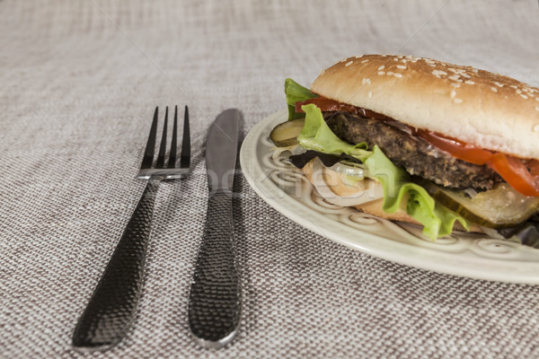 Fresh hamburger with a chop of marbled beef and fresh vegetables on a plate with a fork and knife Stock photo © mcherevan