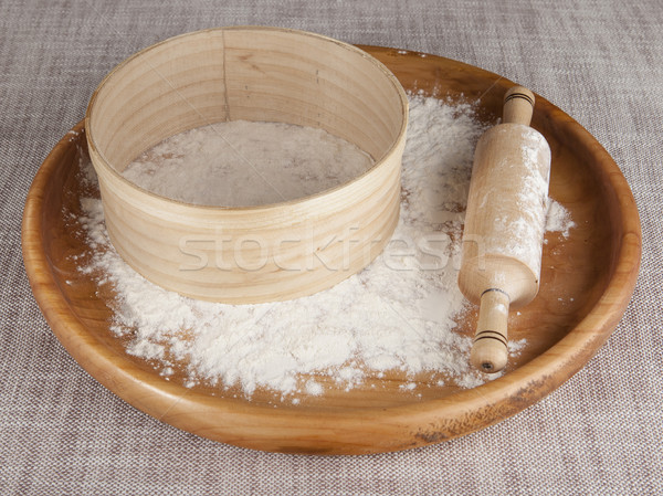 Rolling pin and sieve in the flour on a wooden tray. Stock photo © mcherevan